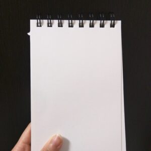 woman's hand holding a blank memo pad - How to Write a Landlord-Tenant Memo